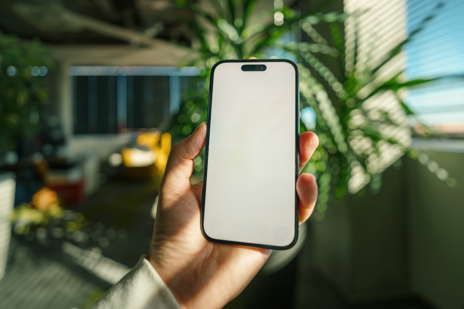 Smartphone mockup green office interior lifestyle workspace. Hand holding modern mobile phone with blank screen in stylish...